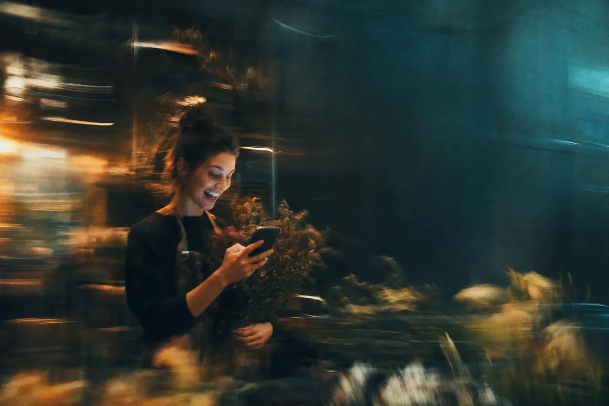 Floristin freut sich über eine neue Anfrage auf ihrem Handy